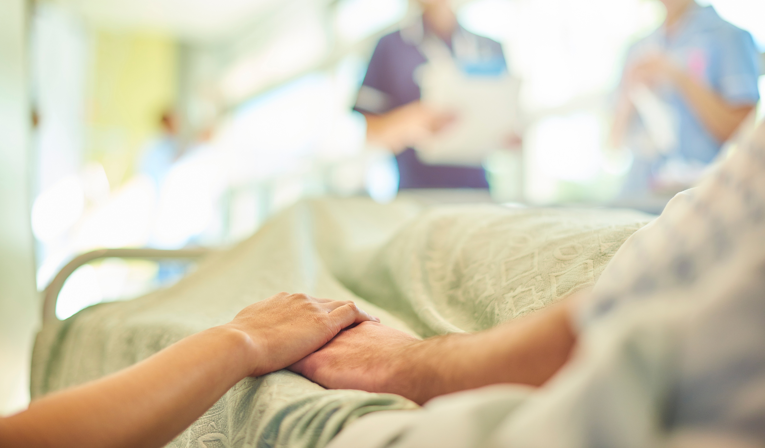 Patient hospitalisé tenant la main d'un proche avant son retour à domicile.