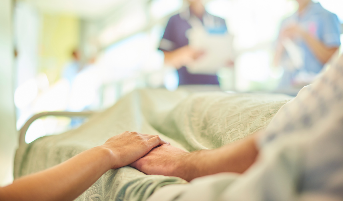 Patient hospitalisé tenant la main d'un proche avant son retour à domicile.
